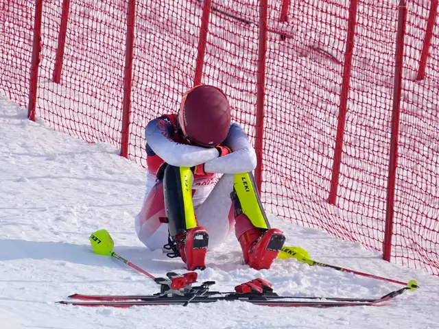 Mikaela Shiffrin sits in the snow with her head down and skis off.